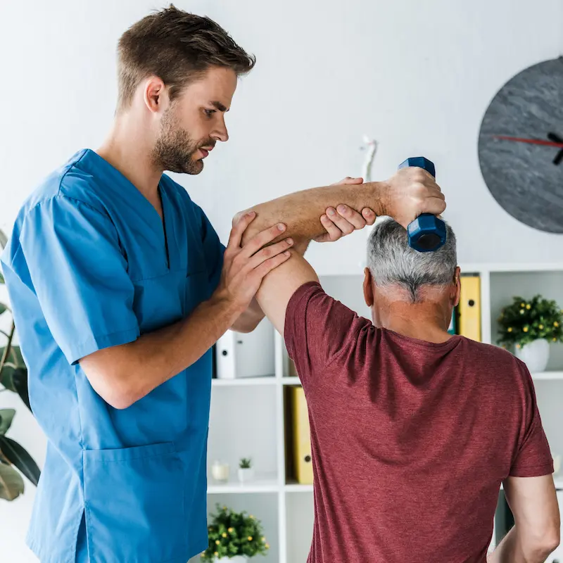 back-view-middle-aged-man-exercising-with-dumbbell-near-handsome-doctor