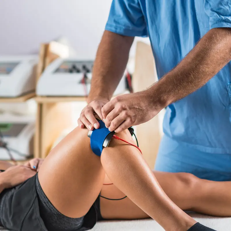 electrical-stimulation-physical-therapy-therapist-positioning-electrodes-patient-s-knee